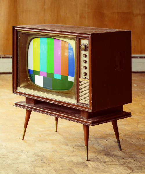 Vintage television with test pattern amidst a rundown home interior.